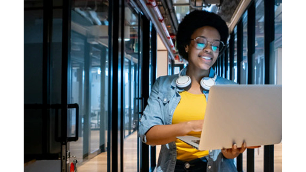 Person using a laptop while standing in a data center aisle